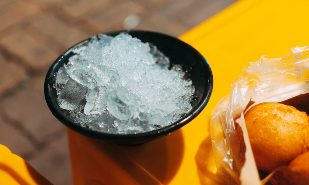 A black bowl filled with ice cubes on a yellow table