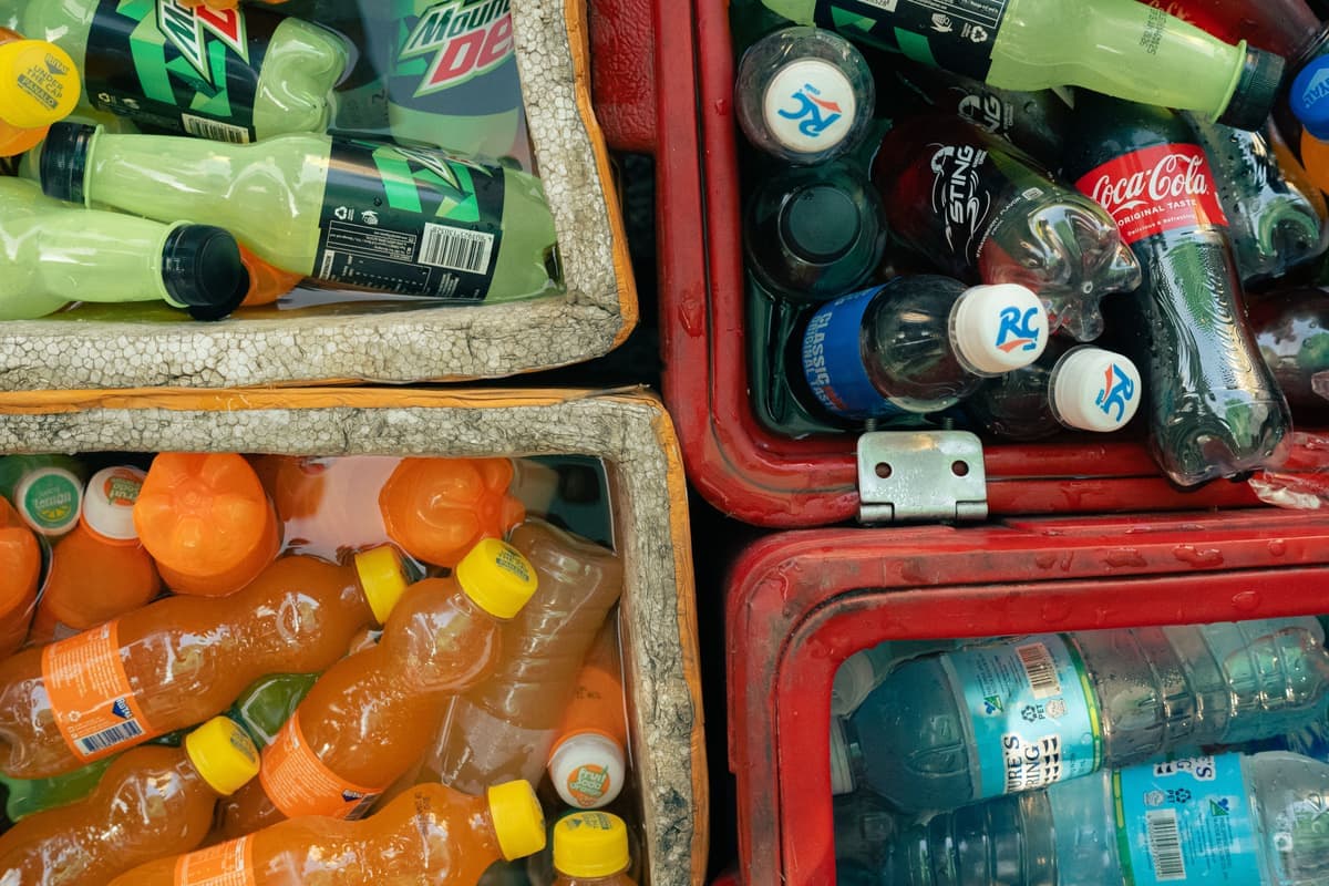 Assorted chilled soft drinks packed in ice in open coolers outdoors