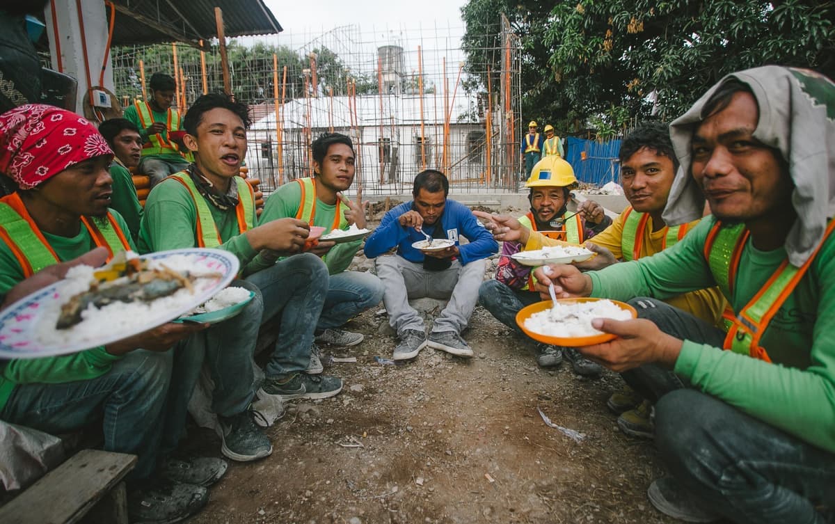 Construction workers sitting together on a lunch break at an outdoor site