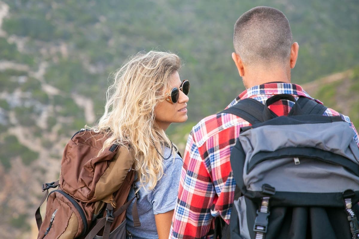 Illustrative stock photo: two hikers with backpacks on a scenic trail