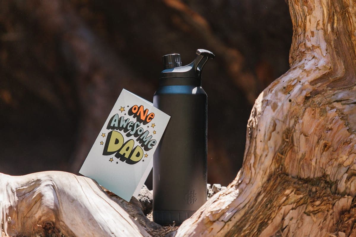 Illustrative stock photo: a black insulated tumbler resting on textured tree bark